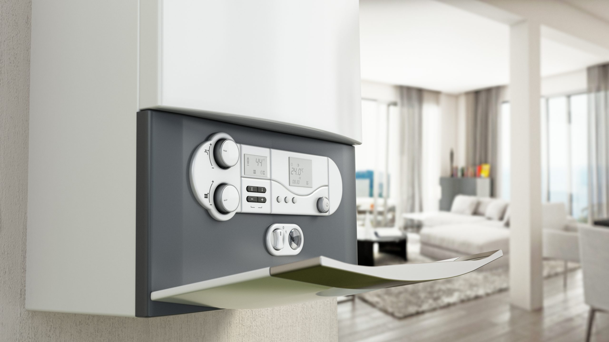 A modern wall-mounted boiler with digital controls is installed in a bright, contemporary living room. The boiler features dials, buttons, and a digital display. In the background, the living area is furnished with a sofa, a small table, and large windows.